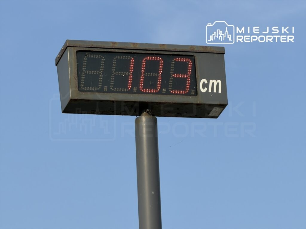 Cyfrowy wskaźnik pokazujący poziom wody w Wiśle, wskazujący 8,03 cm, na tle błękitnego nieba.
