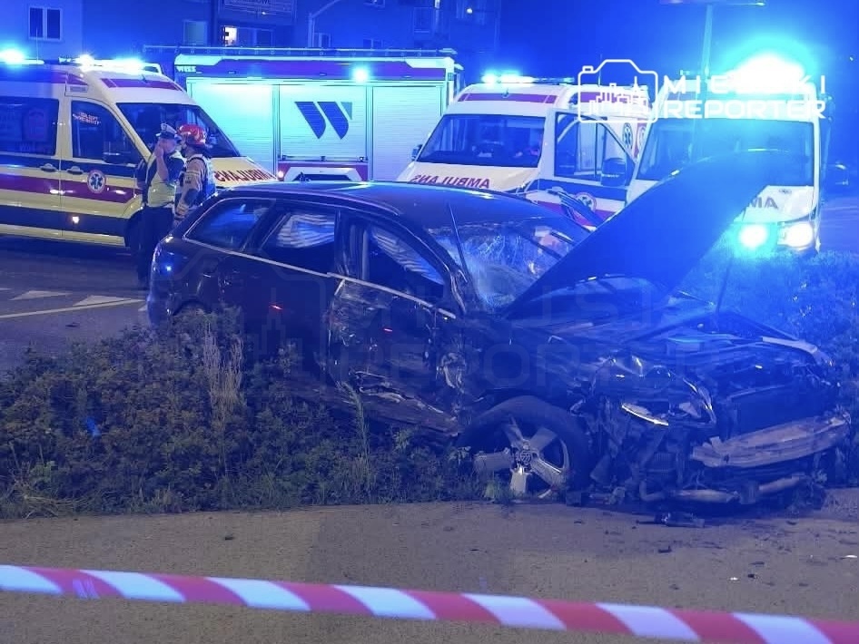 Zniszczony samochód osobowy stoi na poboczu, obok widać karetki z włączonymi sygnałami świetlnymi.
