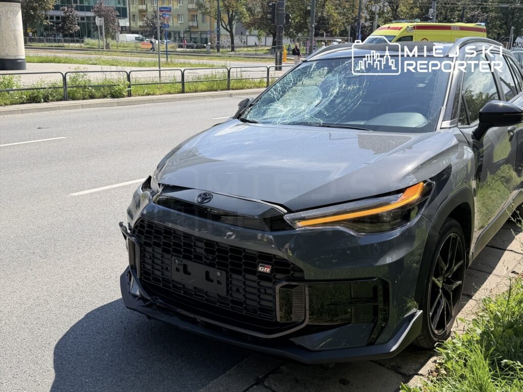 Uszkodzony samochód marki Toyota stojący na poboczu ulicy, z rozbitą szybą czołową i uszkodzoną przednią częścią.