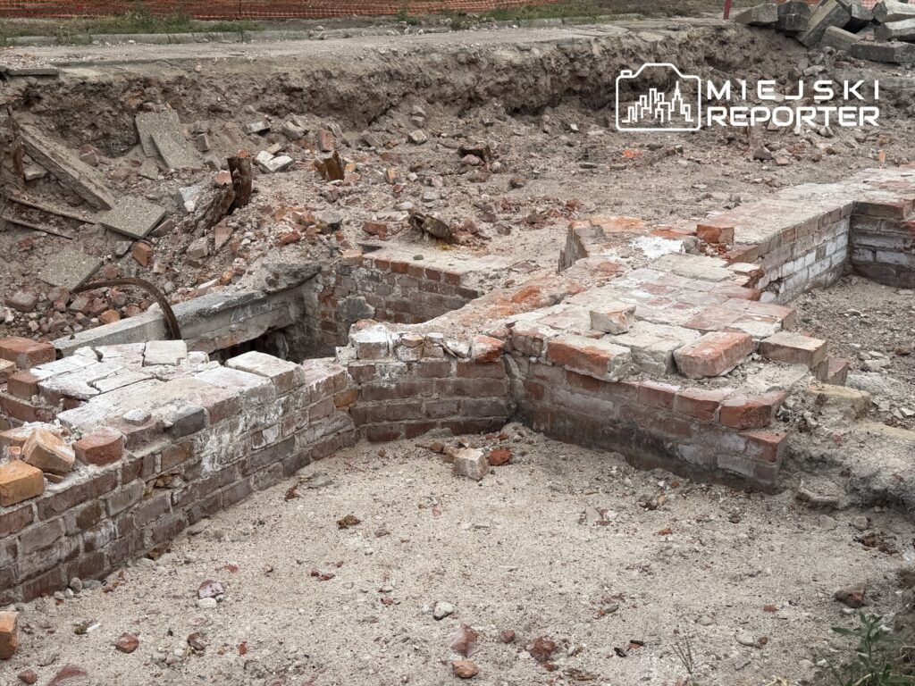 Fragment ceglanej konstrukcji odsłonięty podczas remontu, otoczony gruzem i piaskiem.