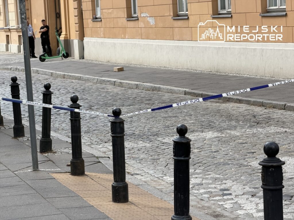 Dwaj policjanci stoją obok zielonego hulajnogi, a ulica jest zabezpieczona taśmą policyjną.