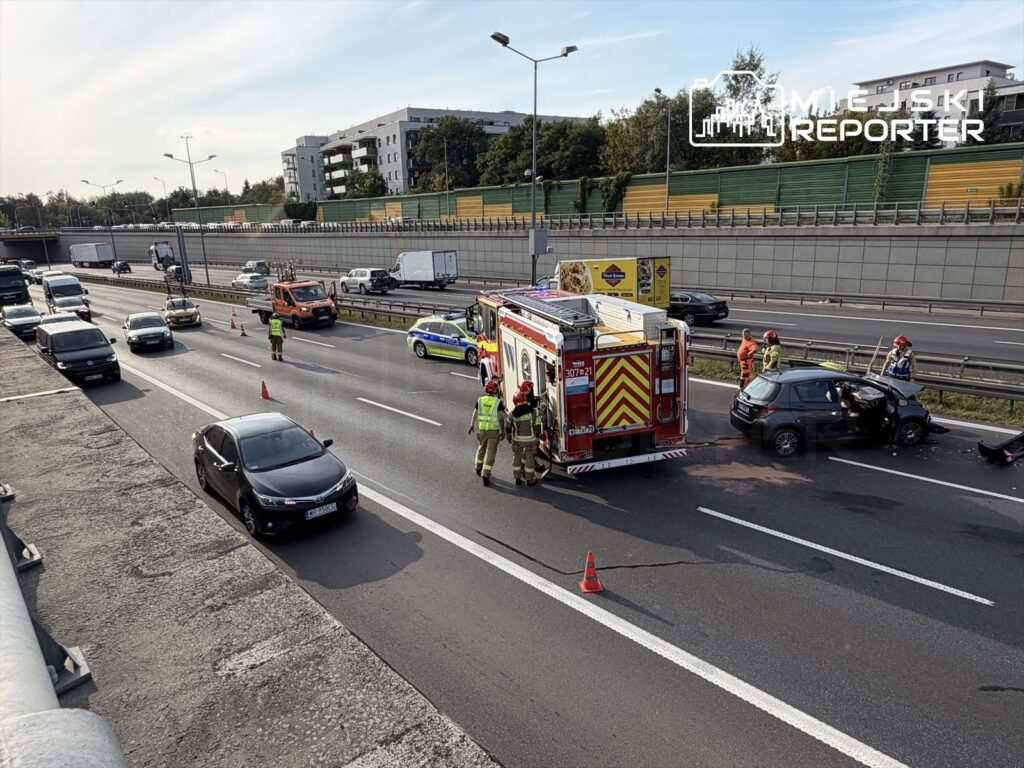 Na drodze S8 zderzenie trzech aut, strażacy udzielają pomocy poszkodowanym, wokół ustawione pachołki.