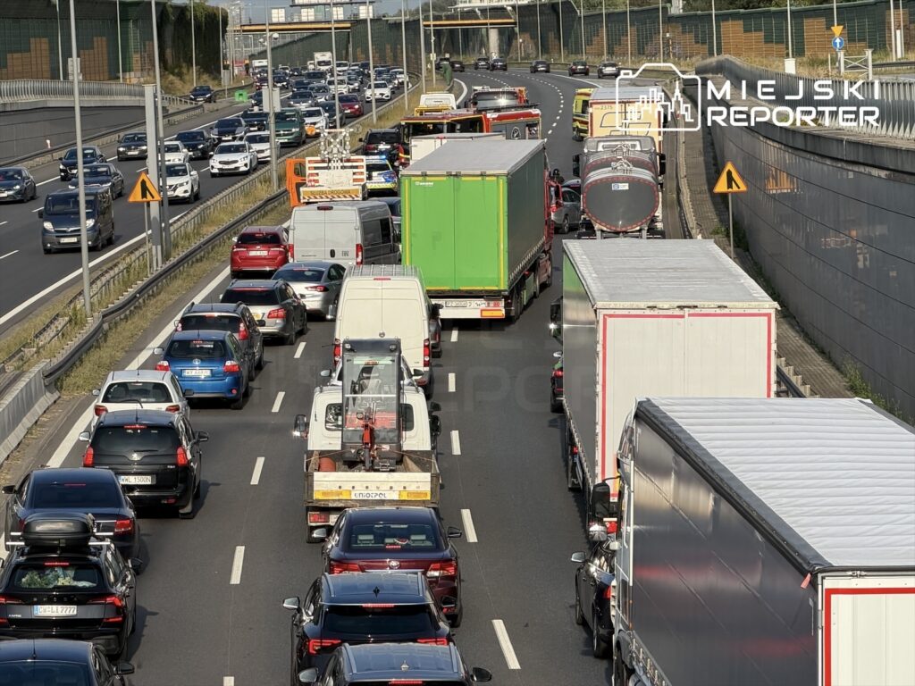 Korek drogowy na autostradzie, z wieloma samochodami osobowymi i ciężarówkami stojącymi w zatorze.