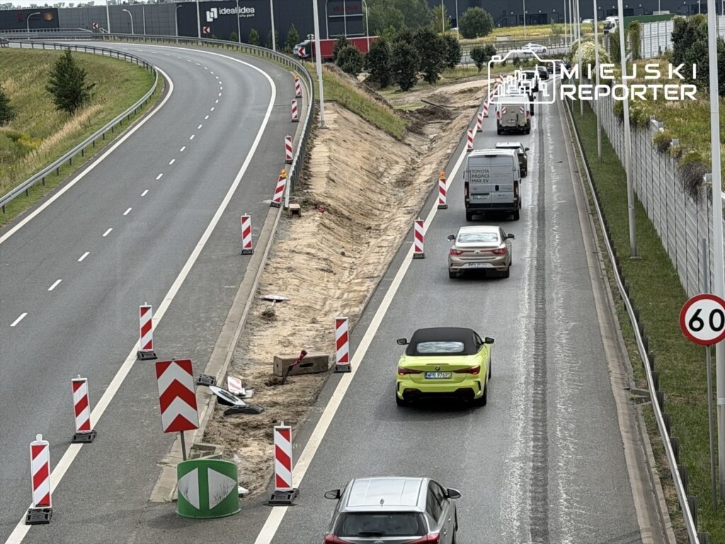 Ruch pojazdów na drodze z oznaczeniami robót drogowych oraz ograniczeniem prędkości do 60 km/h.