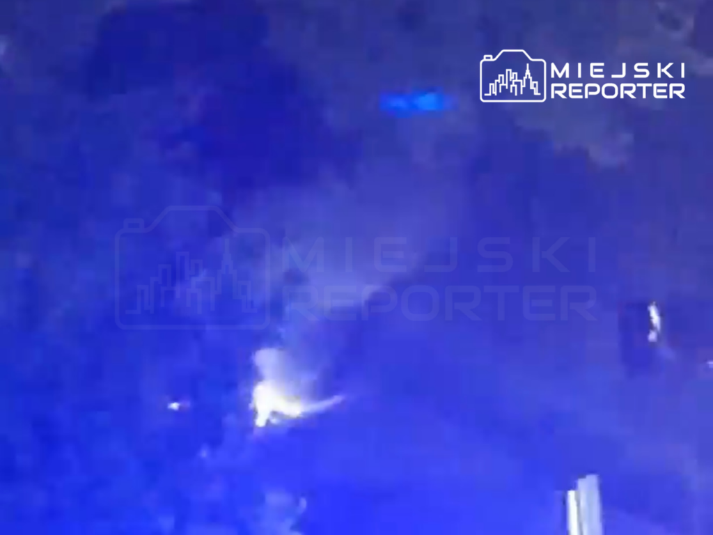 Nieprzyjemne zdarzenie na miejscu pożaru, w tle niebieskie światła pojazdów ratunkowych.