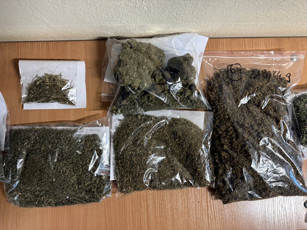 Pakiety z suszem roślinnym leżą na drewnianym stole, w tym różne rodzaje zielonego materiału w przezroczystych woreczkach.