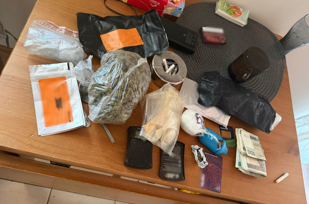 Na stole leżą różne pakunki z substancjami, gotówka, telefon oraz inne akcesoria do porcjowania.