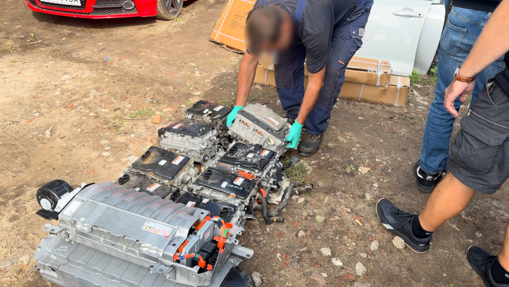 Mężczyzna w rękawiczkach bada zestaw zużytych silników elektrycznych na ziemi w zewnętrznej lokalizacji.