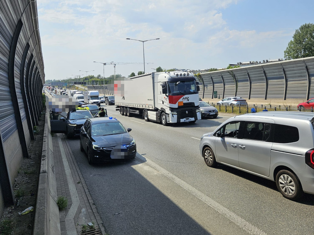 Na drodze zatrzymane samochody osobowe oraz ciężarówki, obok policyjne pojazdy w trakcie interwencji.