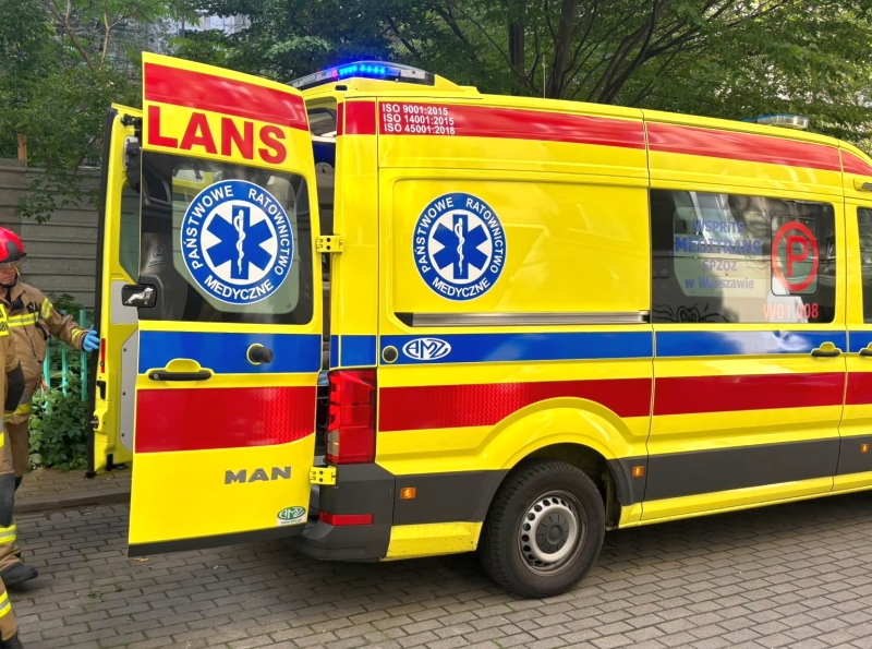 Zespół ratowników medycznych przygotowuje się do akcji przy otwartych drzwiach karetki pogotowia.