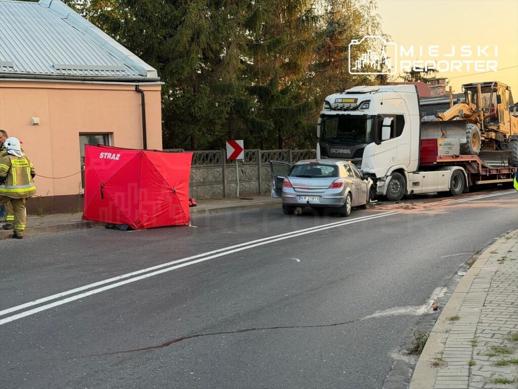 Strażacy pracują przy wypadku drogowym, gdzie ciężarówka z przyczepą zderzyła się z osobowym samochodem na ulicy.
