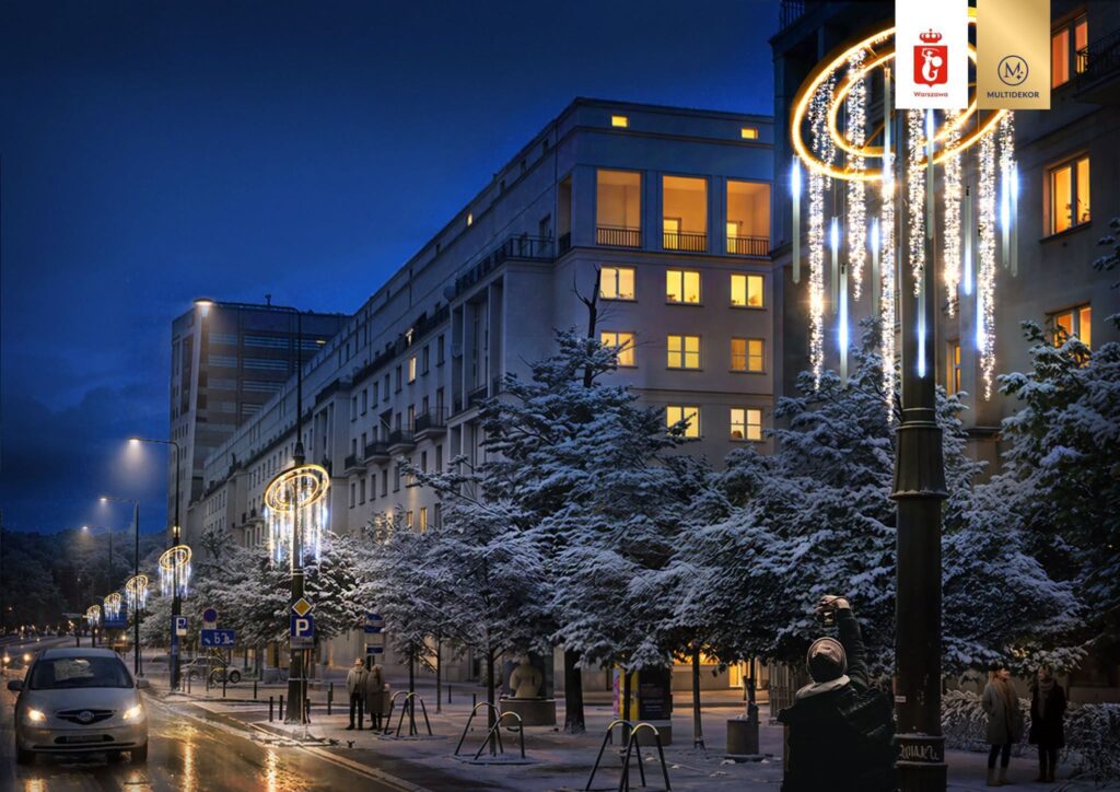 Ulica pokryta śniegiem, oświetlona lampionami z dekoracjami świetlnymi, obok przechodnie rozmawiają.