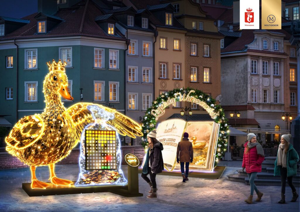 Oświetlona figura kaczki z koroną oraz interaktywna instalacja z legendami warszawskimi w miejskim otoczeniu.