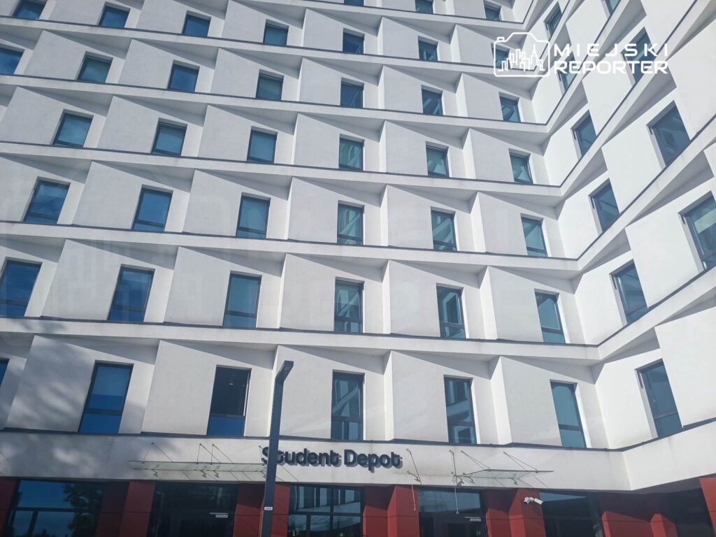 Nowoczesny budynek mieszkalny z białą elewacją i charakterystycznymi oknami, z napisem "Student Depot" na parterze.