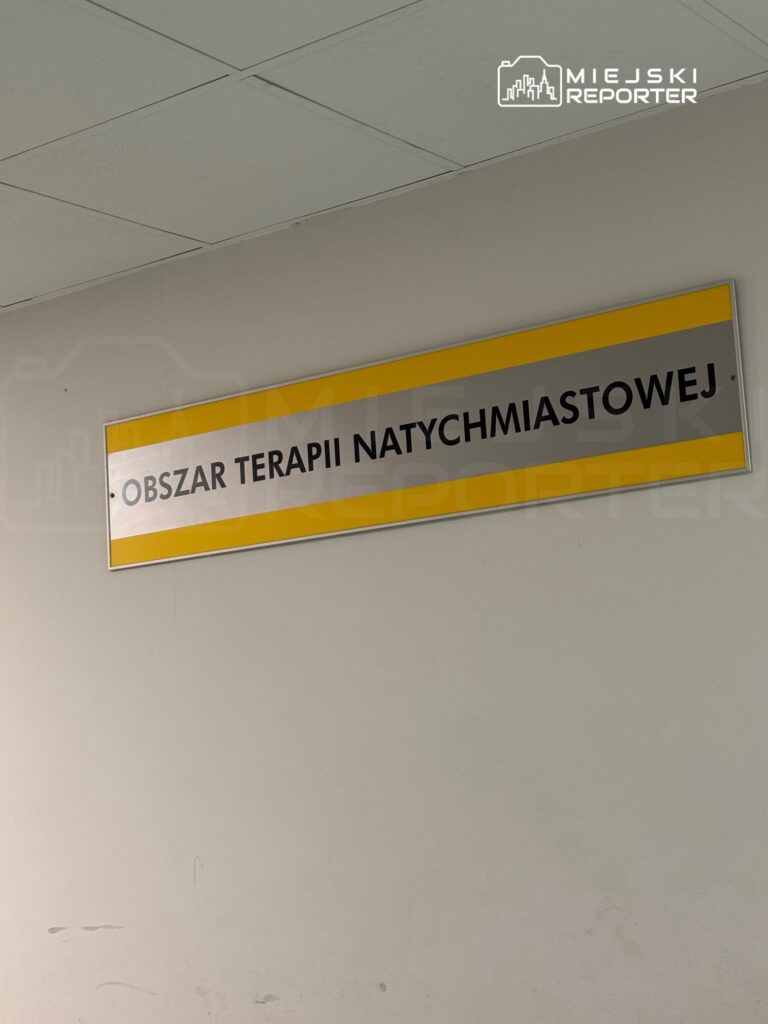 Tablica informacyjna z napisem "Obszar terapii natychmiastowej" umieszczona na ścianie w szpitalu.