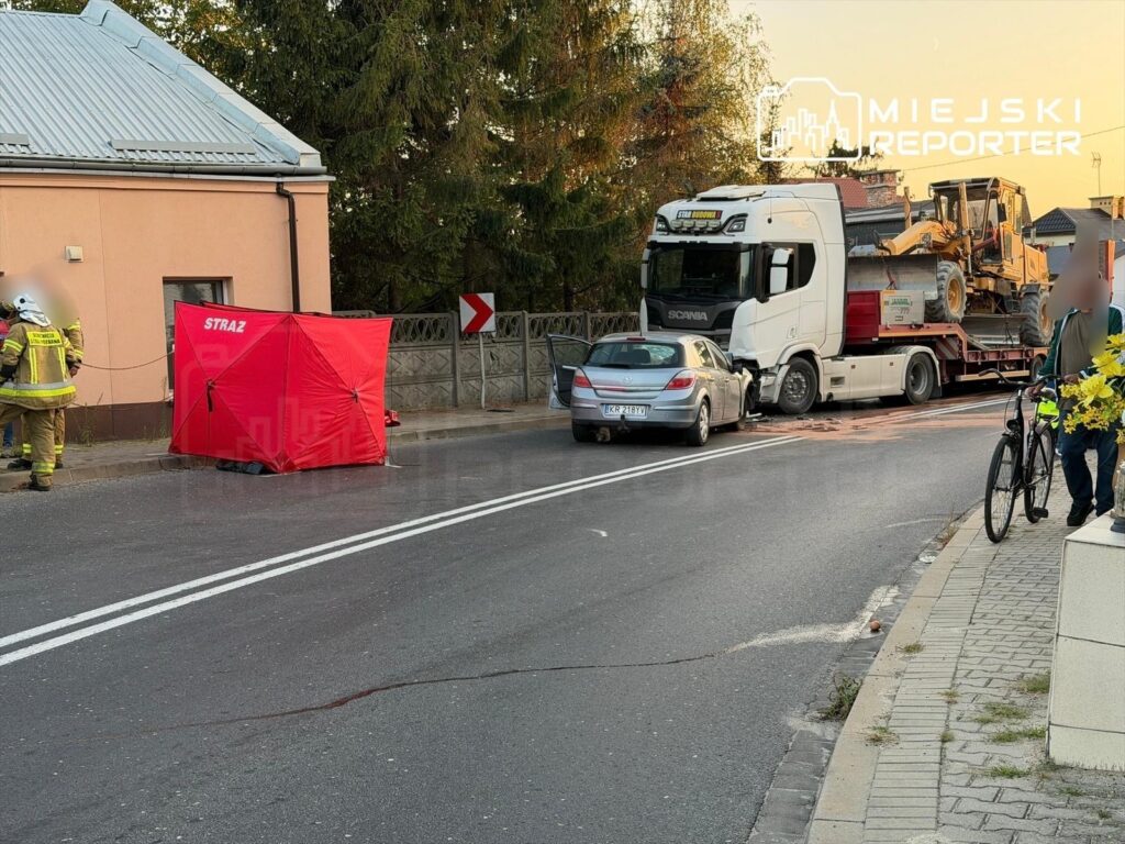 Strażacy zabezpieczają miejsce wypadku drogowego, gdzie ciężarówka z przyczepą uderzyła w osobowy samochód.
