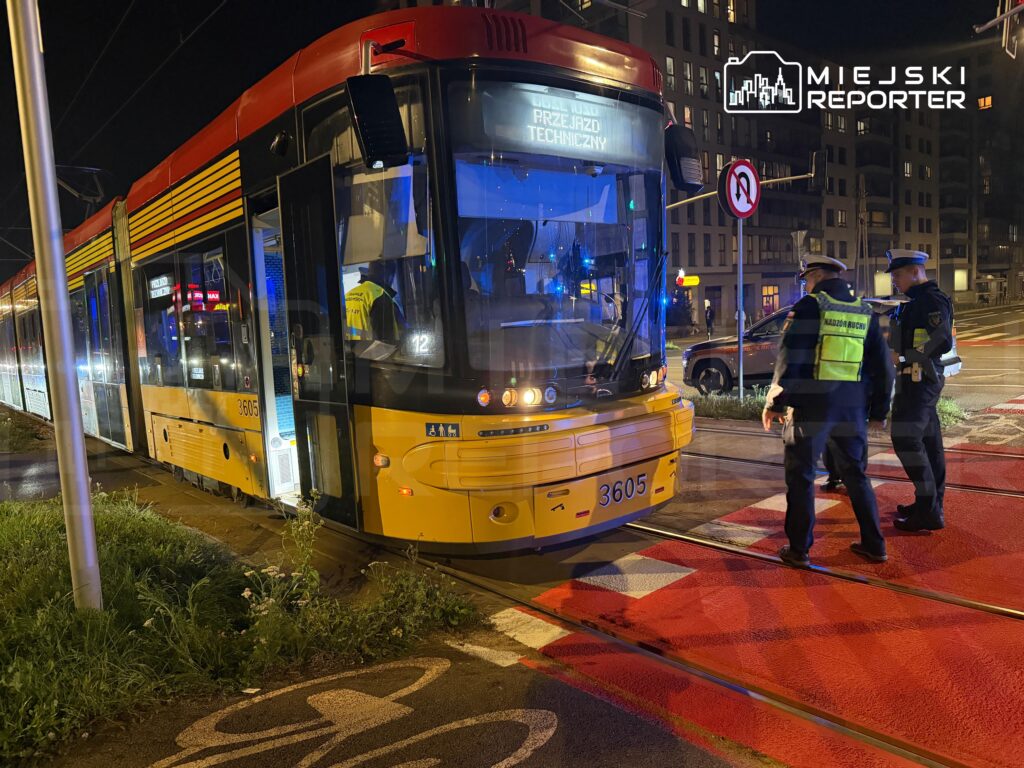 Tramwaj zatrzymany na przejeździe technicznym, a obok dwóch funkcjonariuszy policji rozmawiających z kierowcą.