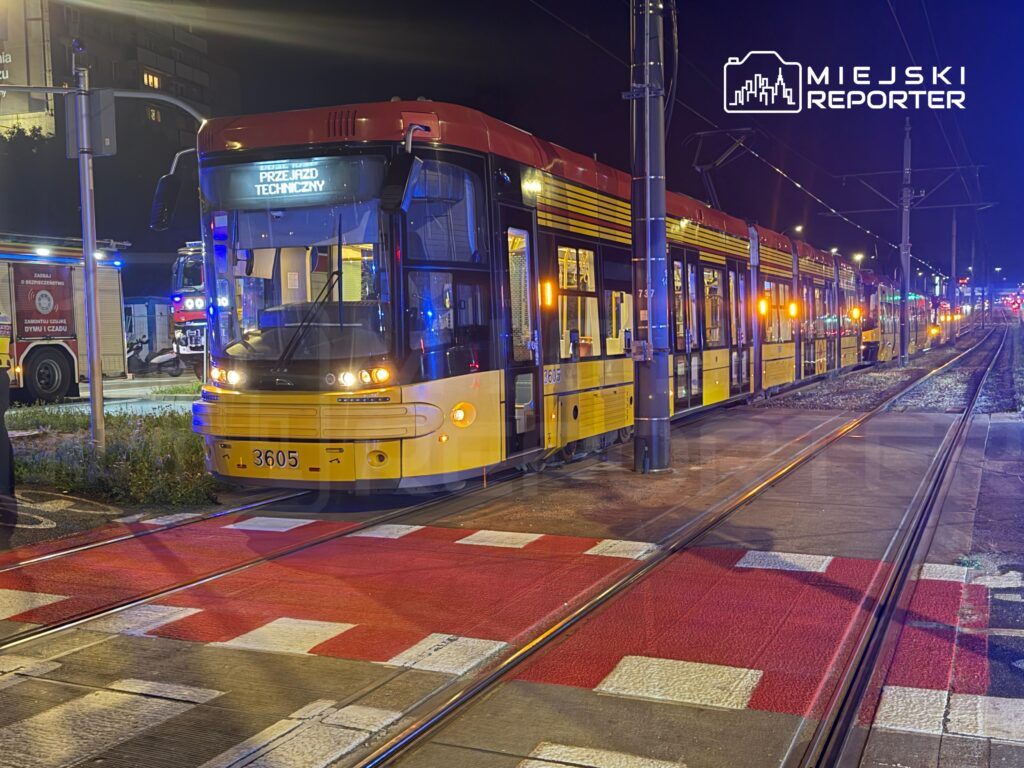 Tramwaj z numerem 3605 zatrzymany na przejeździe technicznym, w tle pojazdy służb ratunkowych z niebieskimi światłami.