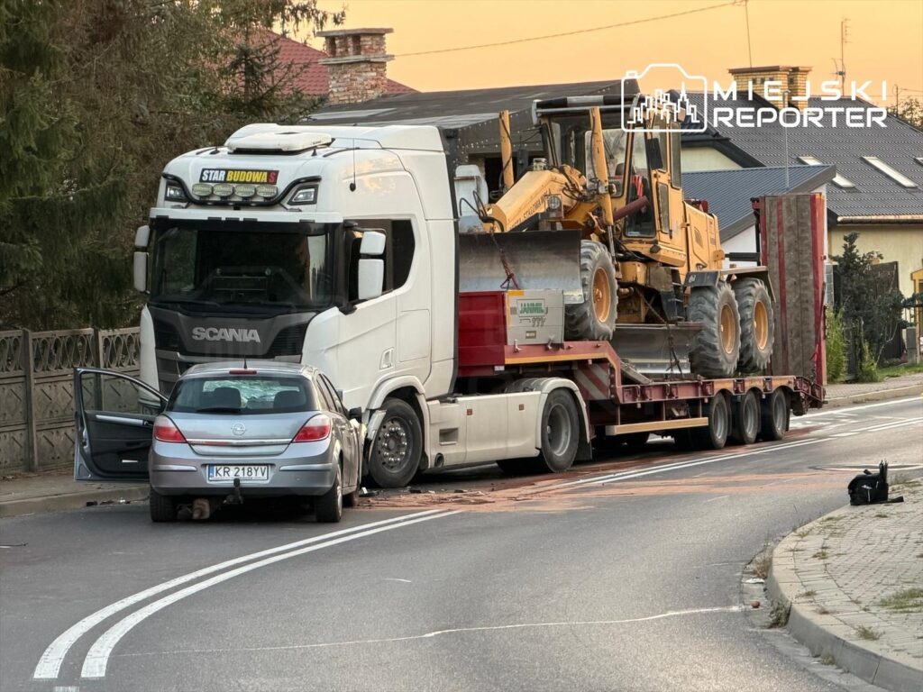 Ciężarówka z logo "STAR BUDOWA" transportująca sprzęt budowlany stoi na drodze obok zaparkowanego samochodu osobowego.