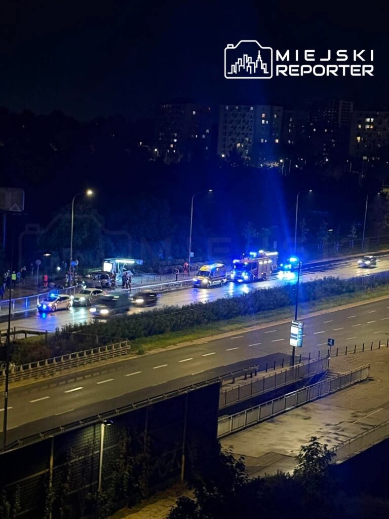 Na drodze nocą, służby ratunkowe z niebieskimi światłami udzielają pomocy przy wypadku drogowym.