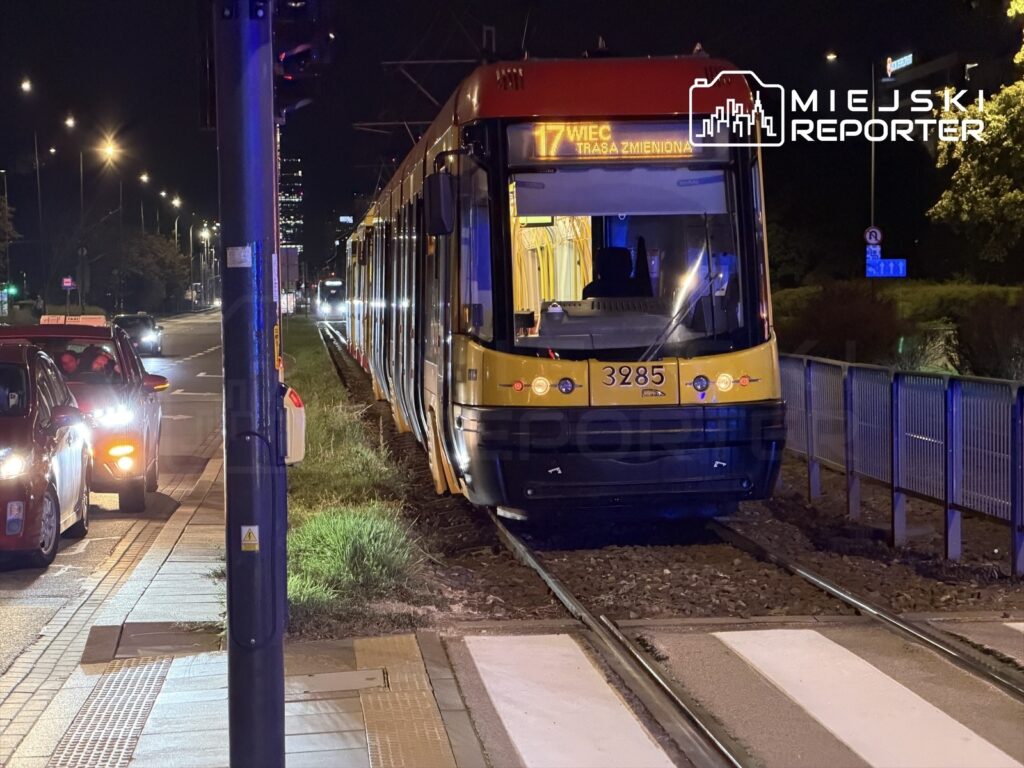 Tramwaj oznaczony numerem 3285 stoi na torowisku w nocy, obok zatrzymujących się samochodów, w tle widać miejskie oświetlenie.