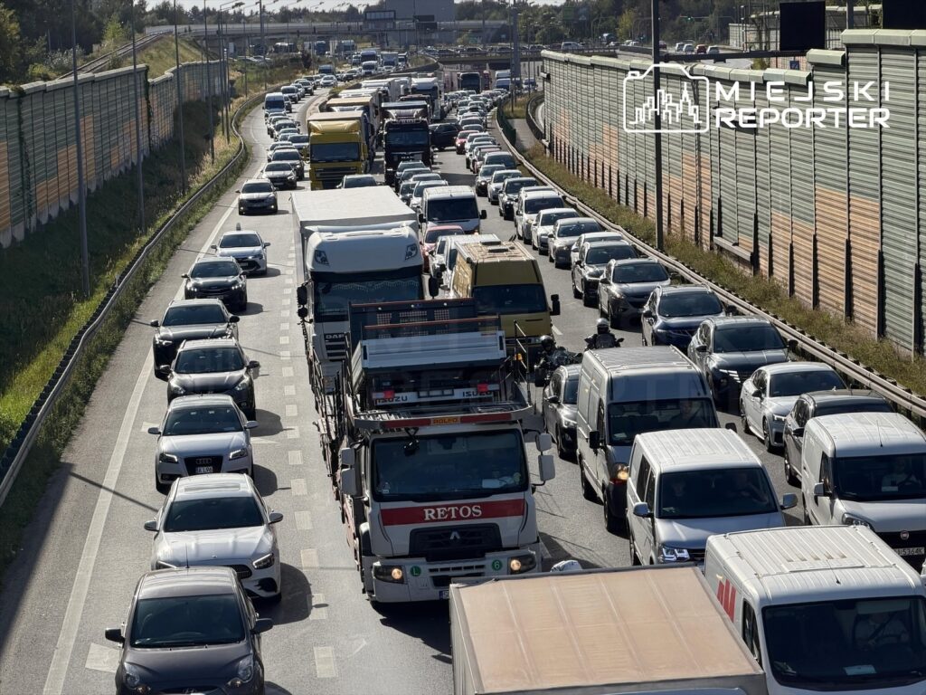 Gęsty ruch samochodowy na drodze szybkiego ruchu, z licznymi pojazdami stojącymi w korku.