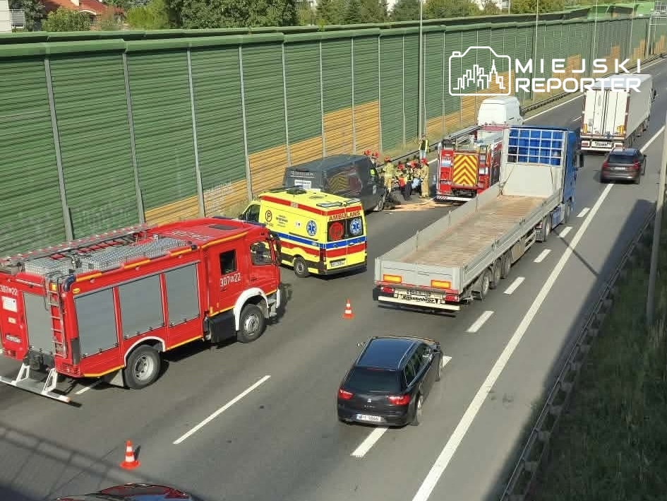 Na drodze S8 zablokowane pojazdy ratunkowe, w tym straż pożarna i karetka, udzielające pomocy poszkodowanemu motocykliście.