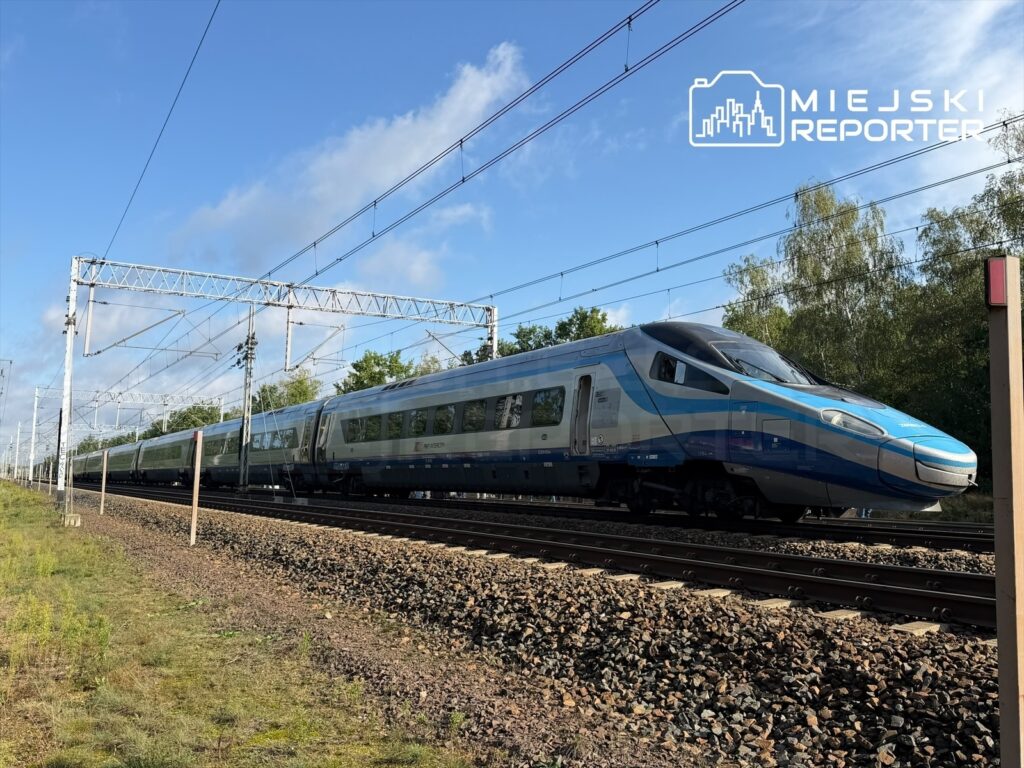 Pociąg Pendolino porusza się po torach w otoczeniu zieleni, w słoneczny dzień.