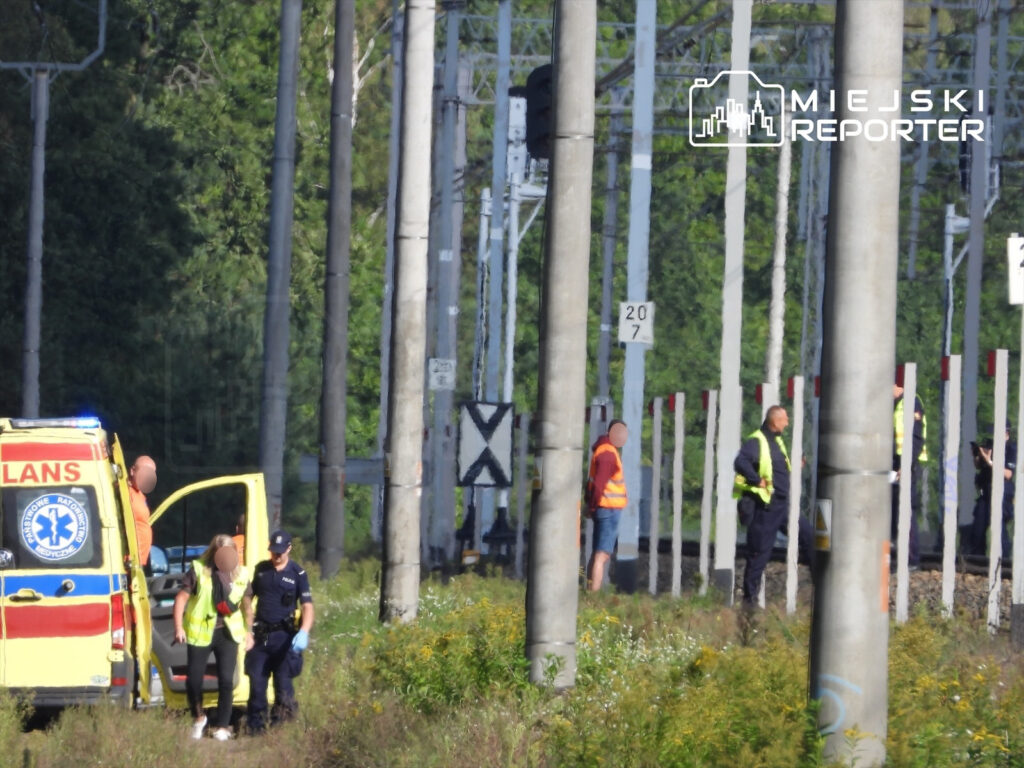 Ratownicy medyczni oraz policja udzielają pomocy na torach kolejowych po wypadku z mężczyzną.