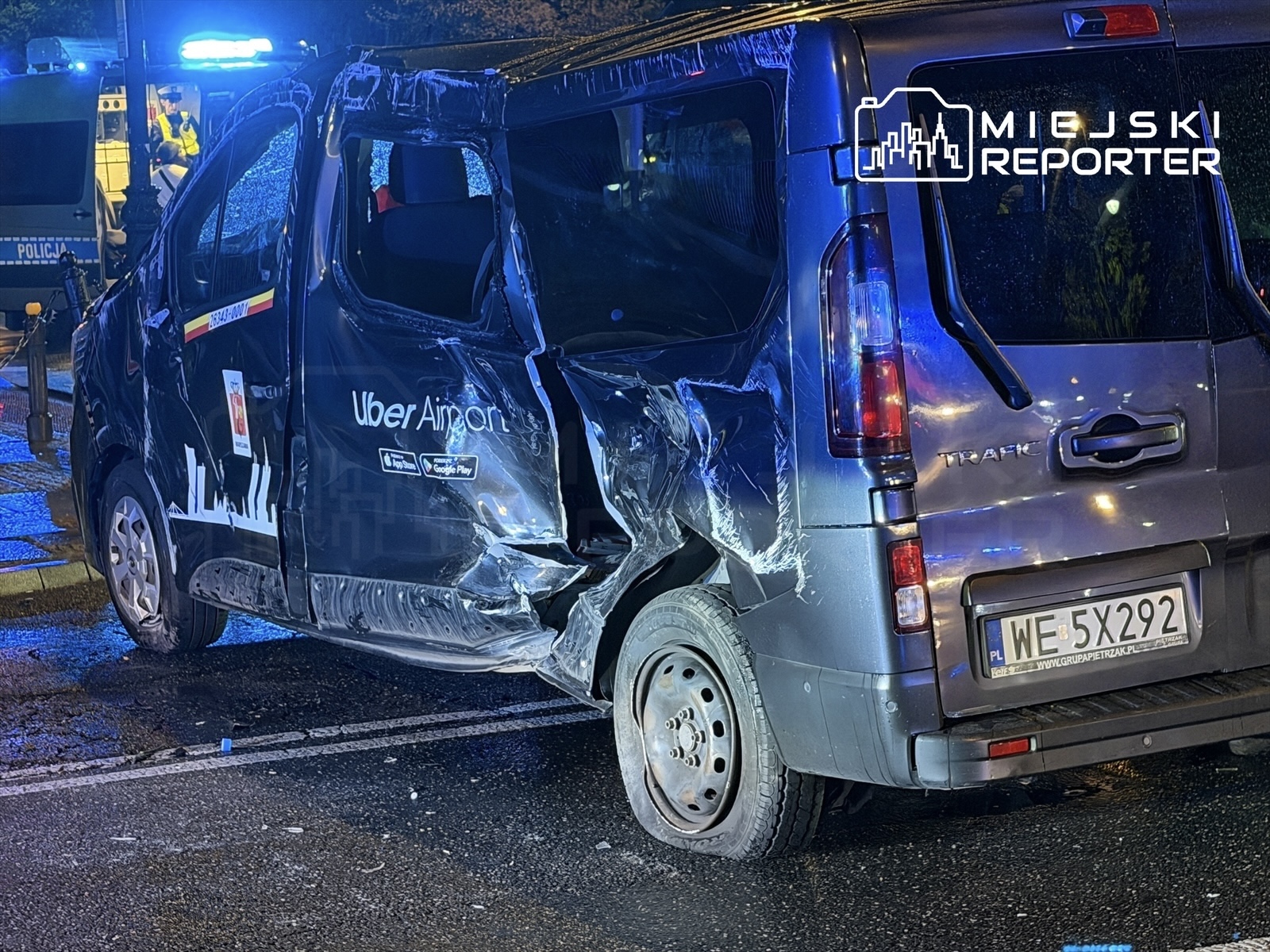 Uszkodzony samochód dostawczy z logo Uber Airport stoi na drodze, obok niego widać radiowóz policyjny.