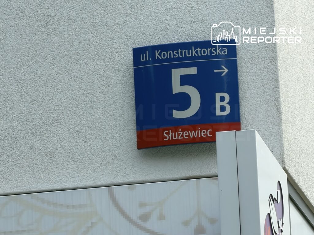 Znak uliczny z nazwą "ul. Konstruktorska 5 B" umieszczony na białej ścianie budynku w Służewcu.
