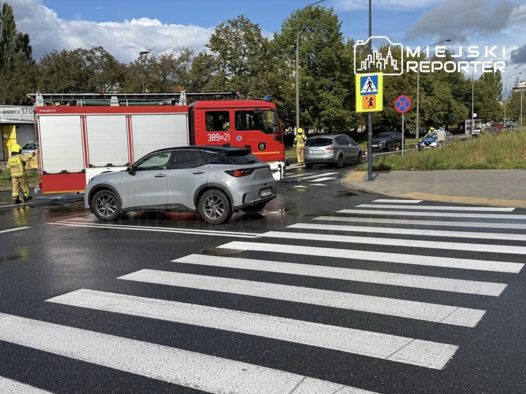 Na przejściu dla pieszych zatrzymany samochód osobowy, obok wóz strażacki i strażacy interweniujący po potrąceniu.