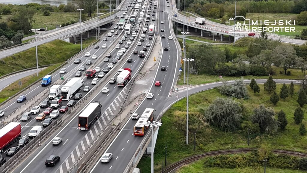 Ruch samochodowy na trasie S8, z dużym natężeniem pojazdów osobowych i ciężarowych, w otoczeniu zieleni.