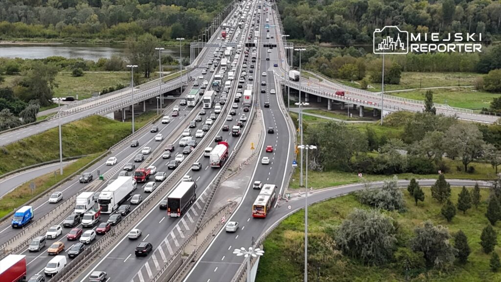 Kierowcy poruszają się w dużym korku na trasie S8, wzdłuż zielonych terenów i rzeki w tle.
