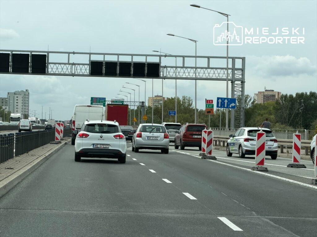 Ruch samochodowy na trasie S8, z dwoma pasami lokalnymi, w tle widoczne znaki drogowe i barierki budowlane.