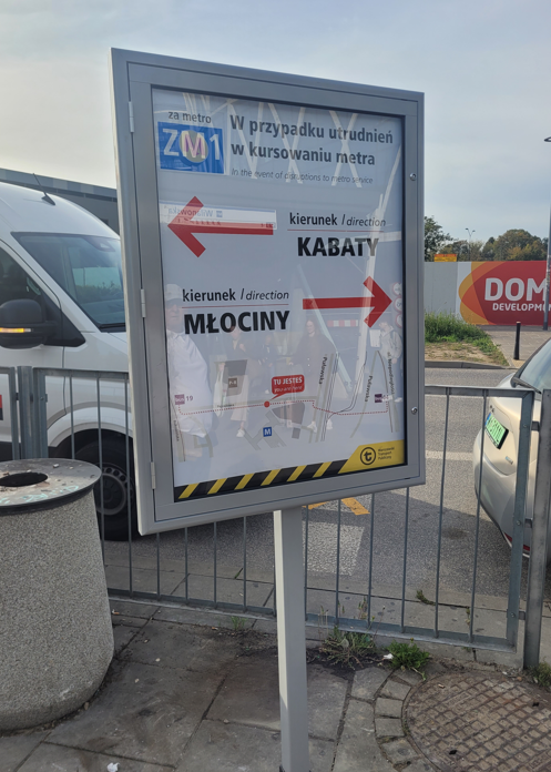 Tablica informacyjna z kierunkami do stacji metra Kabaty i Młociny, z instrukcją w przypadku utrudnień w kursowaniu metra.