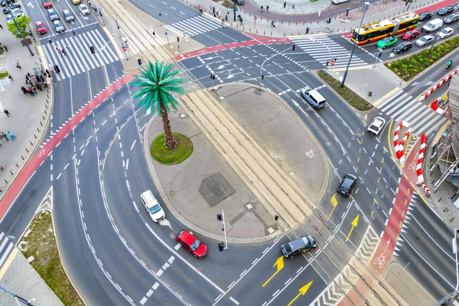 Rondo de Gaulle'a z palmą w centrum, otoczone ruchem samochodowym i pieszym, z widocznymi pasami drogowymi.