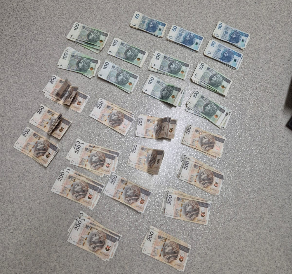 Polskie banknoty o nominałach 50, 100 i 200 złotych rozłożone na szarej powierzchni.