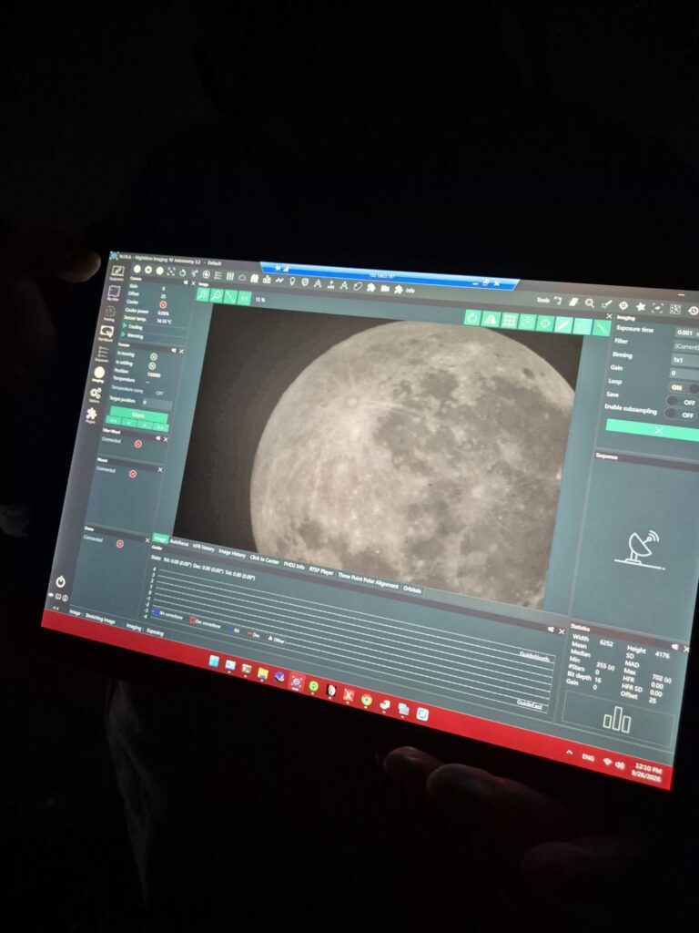Laptop wyświetlający szczegółowy obraz Księżyca w programie do astrofotografii, trzymany w ciemnym otoczeniu.