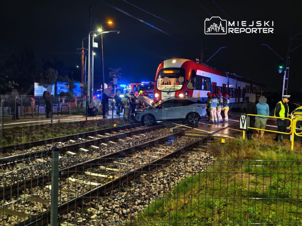 Samochód osobowy zderzył się z tramwajem na przejeździe kolejowym; służby ratunkowe pracują nocą na miejscu wypadku.