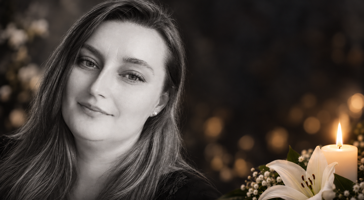 Portret młodej kobiety obok zapalonej świecy i białych kwiatów na ciemnym tle.