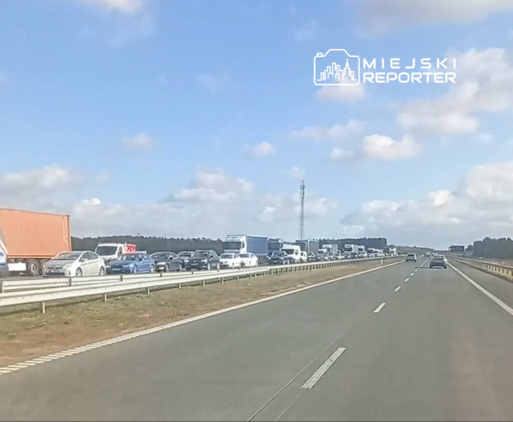 Samochody stoją w korku na jezdni za barierą, podczas gdy prawy pas drogi pozostaje przejezdny.
