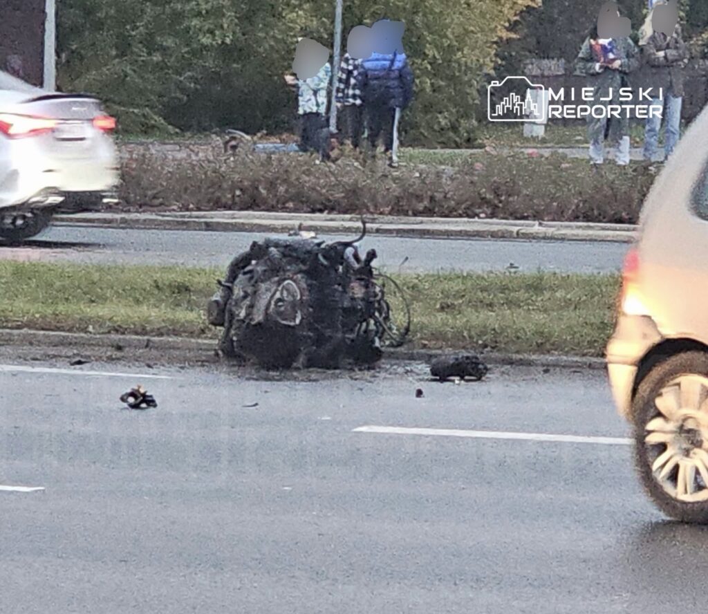 Rozbity motocykl leży na jezdni, a obok niego widać porozrzucane szczątki pojazdu.