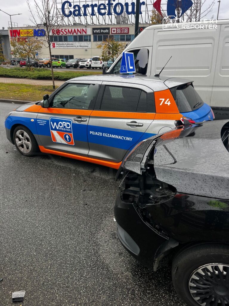 Uszkodzony tył czarnego samochodu obok auta egzaminacyjnego WORD Warszawa na parkingu przy centrum handlowym.