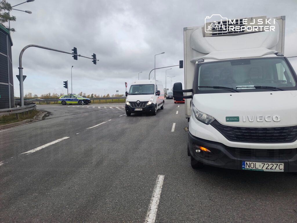 Samochód dostawczy Iveco stoi na skrzyżowaniu, a w tle widać radiowóz i drugą furgonetkę.
