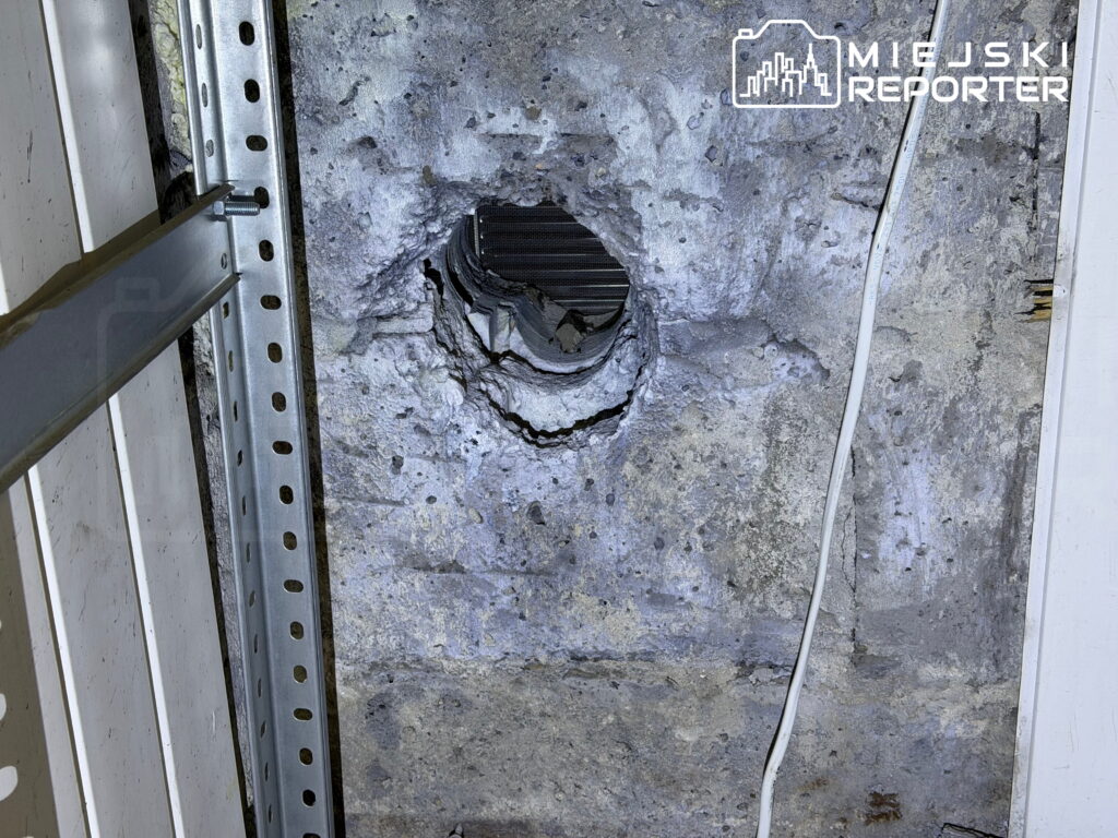 Otwór wentylacyjny w uszkodzonej, surowej ścianie obok metalowego stelaża i przewodu elektrycznego