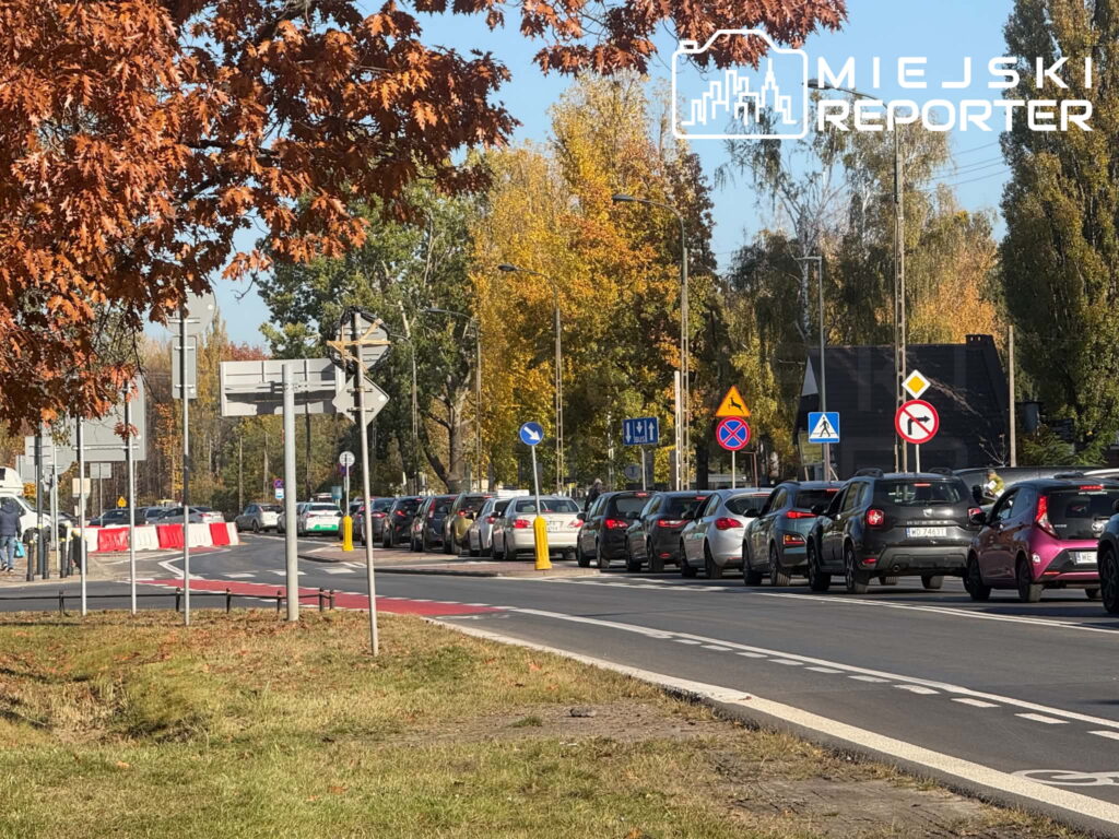 Korki na miejskiej ulicy z długim sznurem samochodów i jesiennymi drzewami w tle