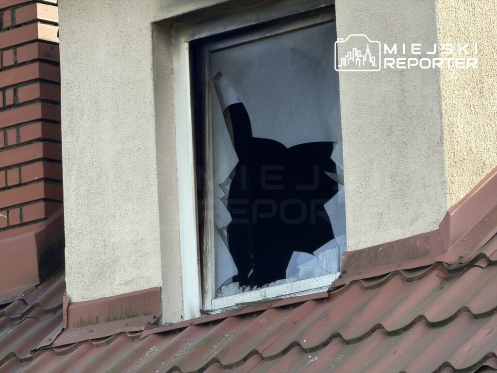 Wybite okno w ścianie budynku nad czerwonym dachem pokrytym dachówką.