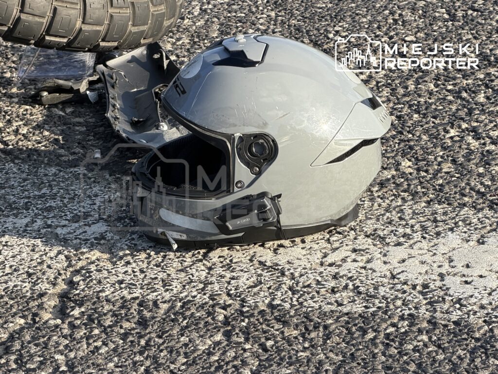 Uszkodzony kask motocyklowy leży na jezdni pod kołem samochodu ciężarowego