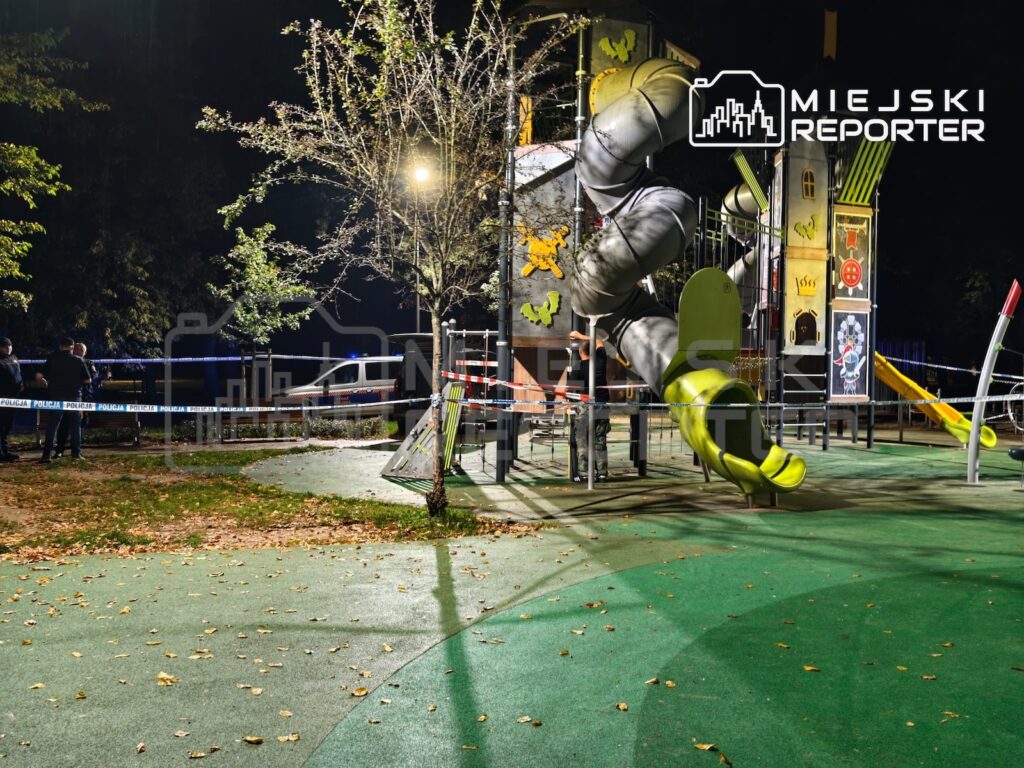 Oświetlony plac zabaw z dużą konstrukcją ze zjeżdżalniami, otoczony policyjną taśmą nocą.